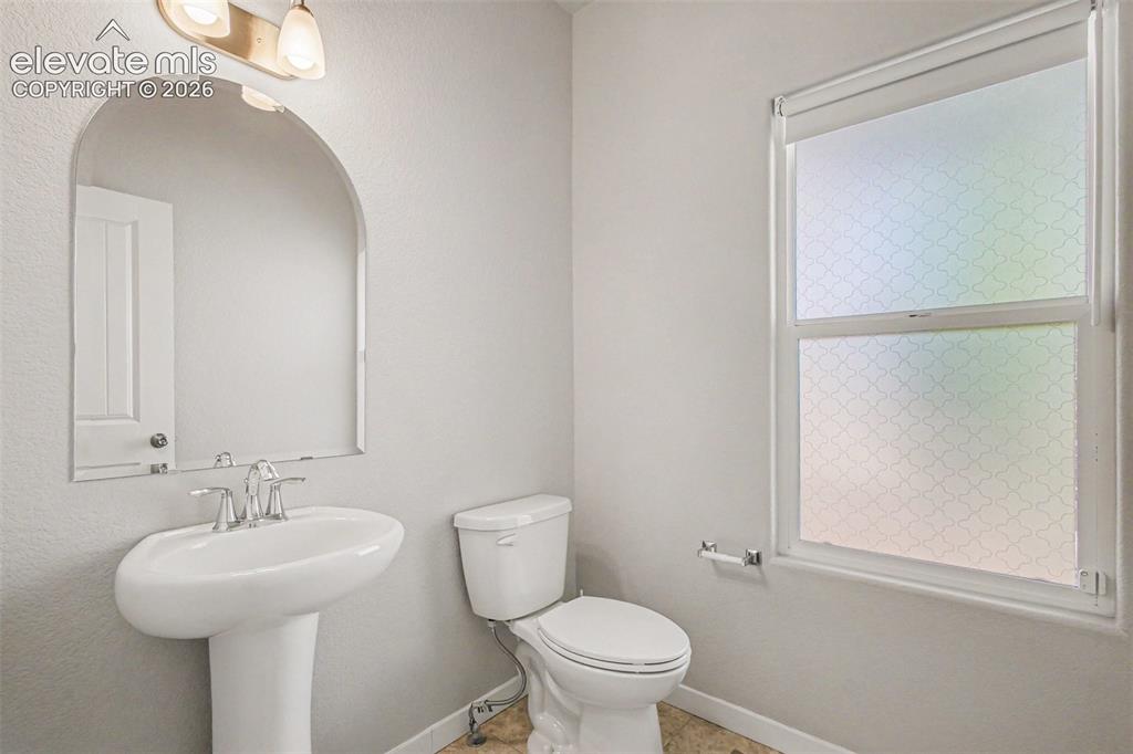 Image 17 of 39: Pedestal sink with chrome faucet, arched frameless mirror, and a two-bulb v