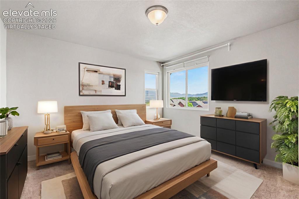 Image 19 of 39: Virtually Staged - Light-filled bedroom featuring a large window, neutral w
