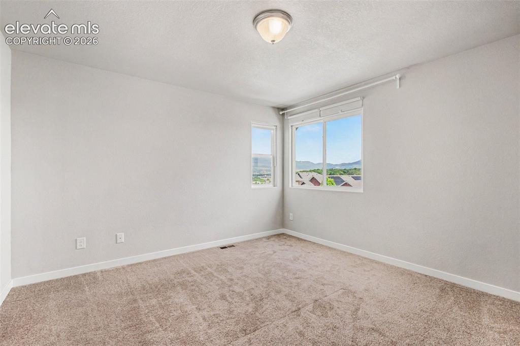 Image 21 of 39: Bright room with two large windows offering a scenic backdrop of mountains