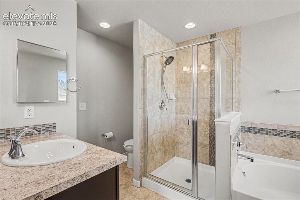 Image 22 of 39: Bathroom featuring a glass-enclosed shower, a built-in tub, and a vanity wi