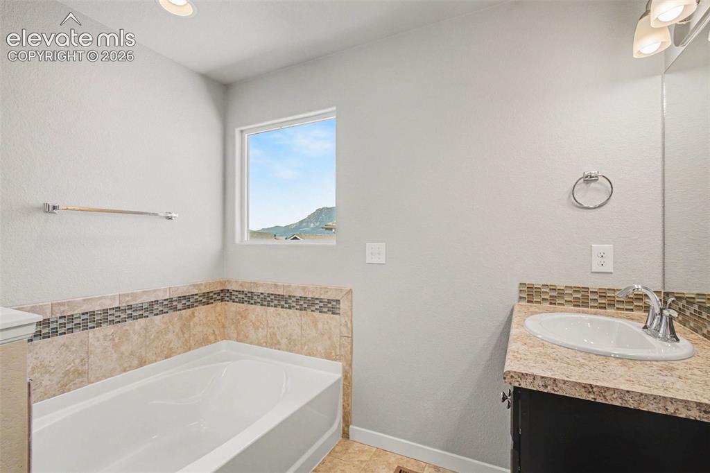 Image 26 of 39: Bathroom featuring a built-in tub with tile surround, a mosaic tile accent