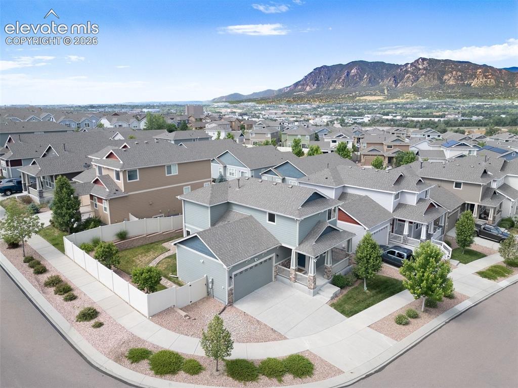 Image 38 of 39: Corner lot property with a light blue exterior, featuring a covered front p