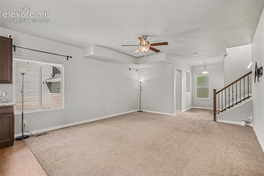 Image 6 of 39: Living space featuring a tray ceiling with a ceiling fan, a sliding glass d