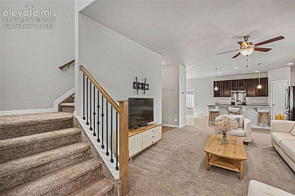 Image 7 of 39: Virtually Staged - living room with carpet and stairs to upper level. Open