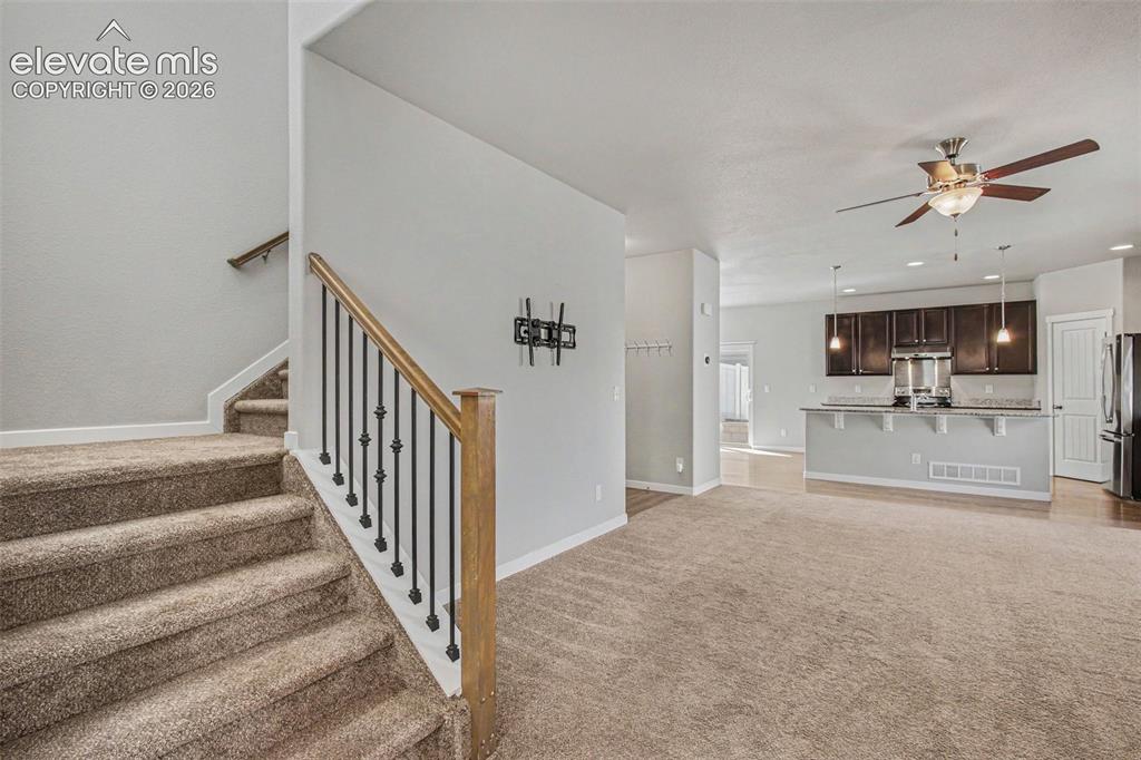 Image 8 of 39: iving room with carpet and stairs to upper level. Open concept roof with li