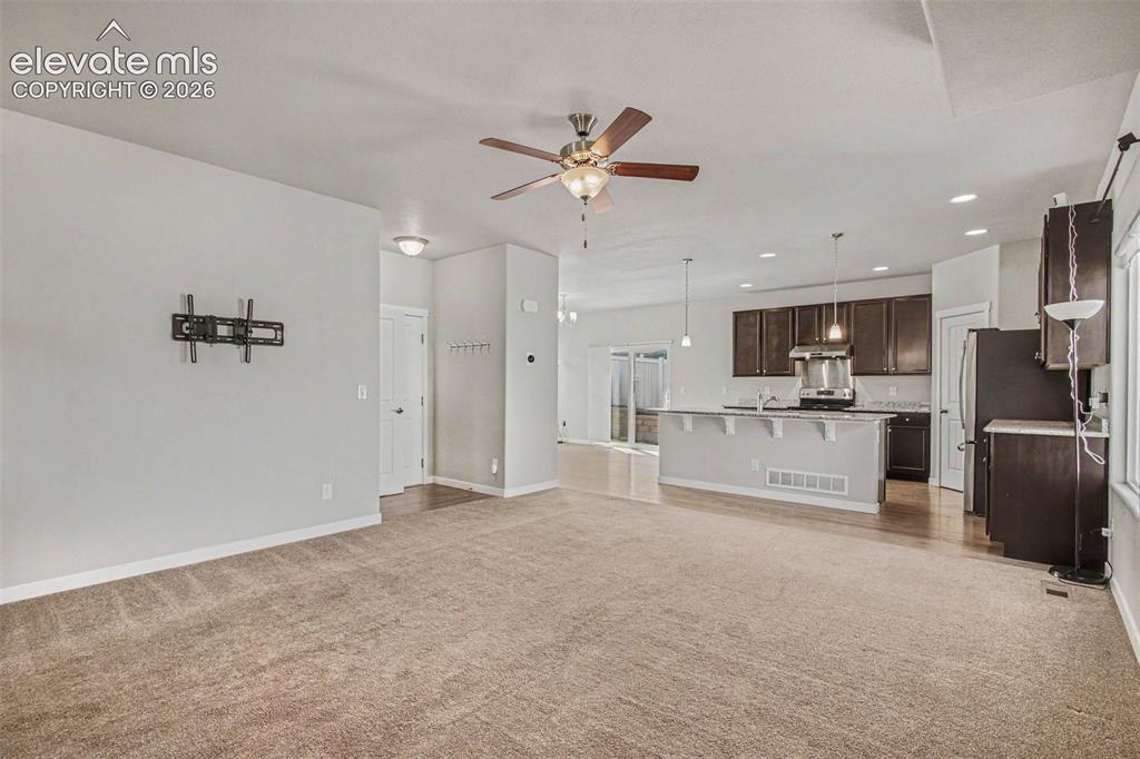 Image 9 of 39: Spacious open-concept living area featuring plush carpeting, a ceiling fan