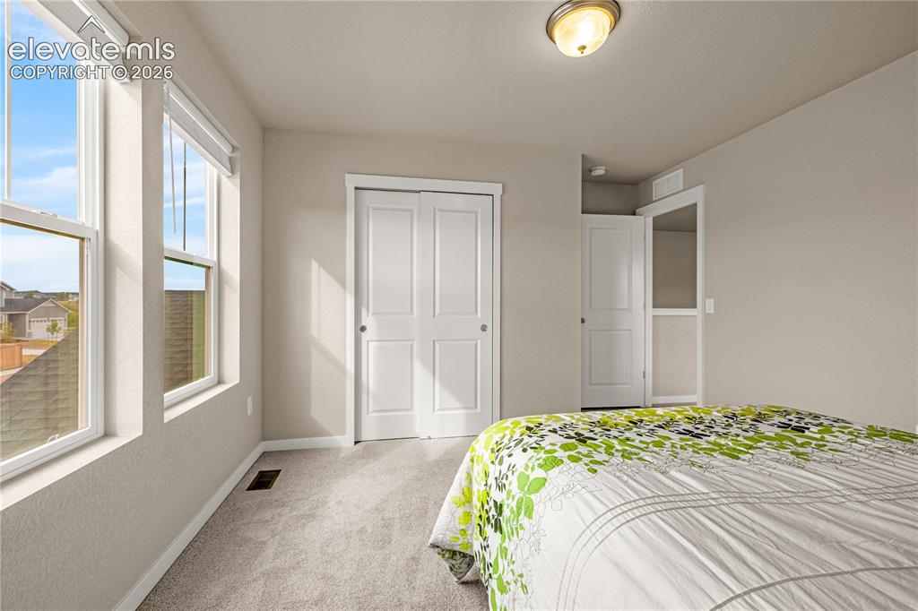 Image 15 of 30: Carpeted room with two double-hung windows, two bi-fold doors, and a flush