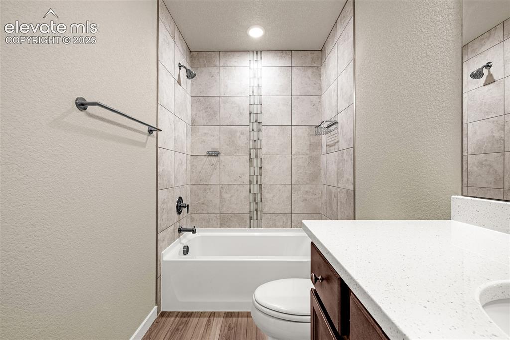 Image 20 of 30: Bathroom featuring a white tub, tiled shower surround, dark wood-finish van