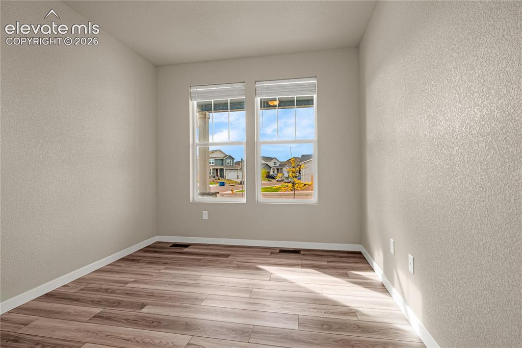 Image 23 of 30: Dual windows with blinds, wood-finish flooring, and light-toned textured wa