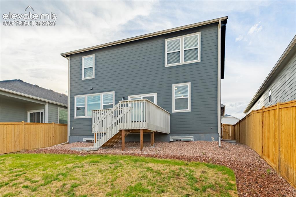 Image 25 of 30: Siding exterior with multiple windows, elevated wooden deck with stairs, fe
