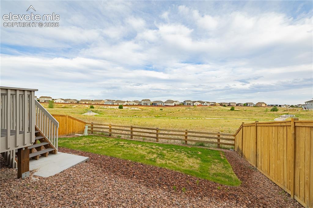 Image 26 of 30: Expansive backyard featuring a manicured lawn, a wooden fence, and a multi-