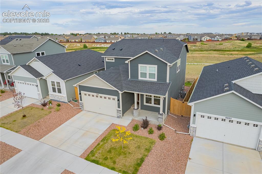 Image 29 of 30: Two-story exterior with dark gray siding, an attached two-car garage, stone