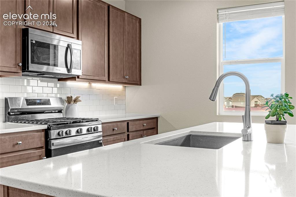 Image 3 of 30: Kitchen featuring wood-finish cabinetry, stainless steel appliances, white