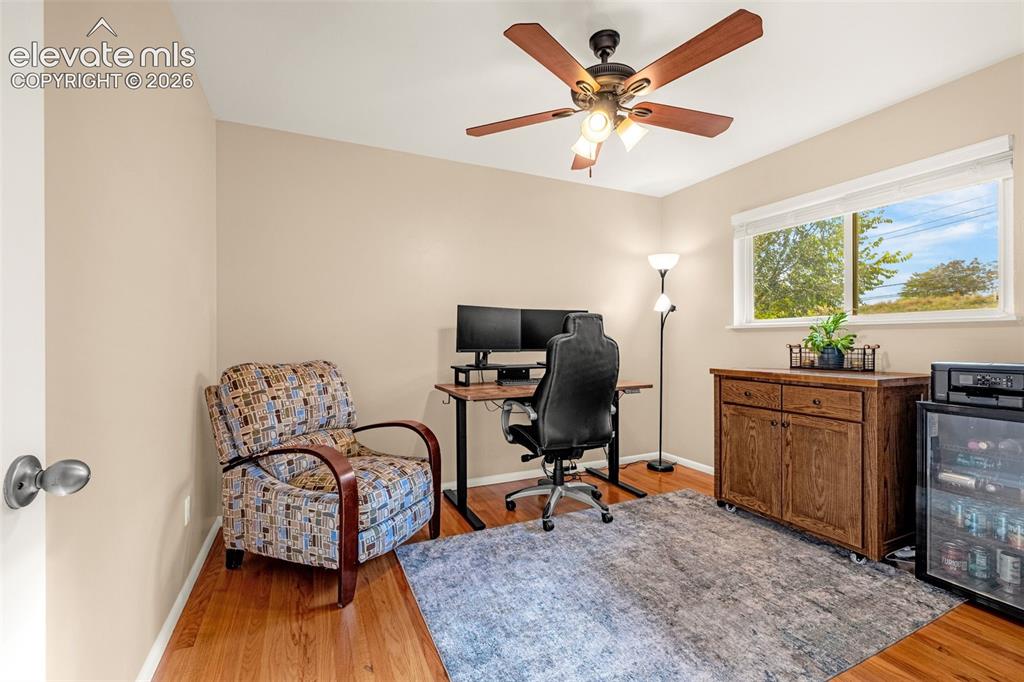 Image 10 of 27: Secondary bedroom on the main level with hardwood flooring, a window provid