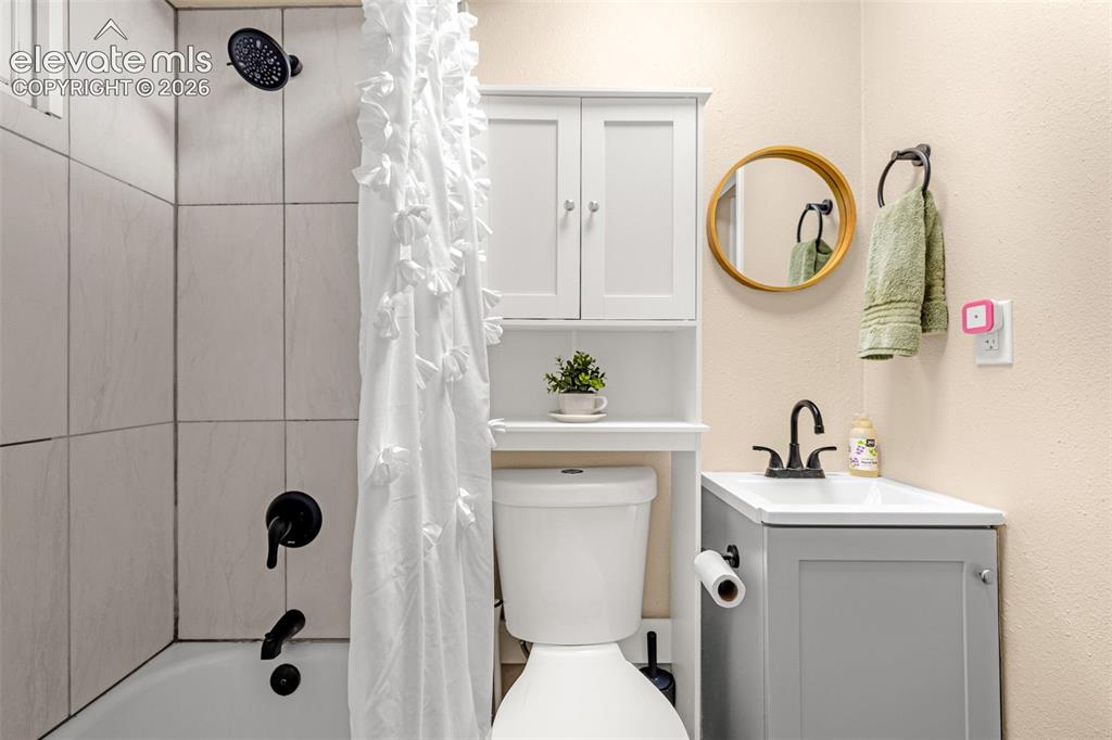Image 16 of 27: Full Basement Bathroom featuring a shower-over-tub combination with tile su