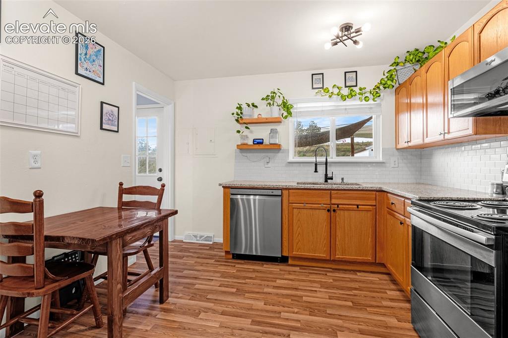 Image 2 of 27: Laminate wood-finish flooring, wood cabinetry, granite countertops, stainle