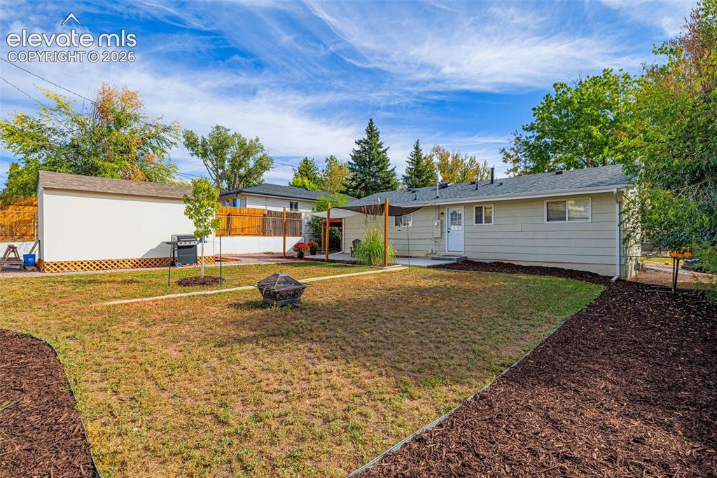 Image 20 of 27: Expansive backyard featuring a dedicated fire pit area, a storage shed, and