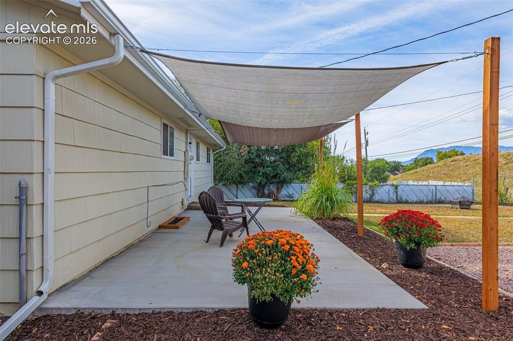 Image 21 of 27: Outdoor concrete patio featuring a shade sail, concrete surface, and landsc