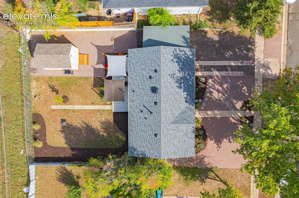 Image 22 of 27: Gable roofline, detached shed, shade sails, gravel hardscaping, and landsca