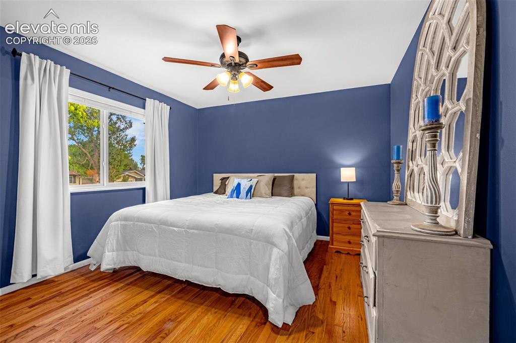 Image 7 of 27: Primary bedroom with king size bed, hardwood flooring, ceiling fan with int