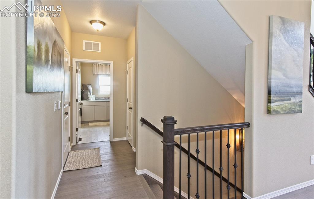 Image 4 of 25: Hall featuring an upstairs landing and dark wood-type flooring