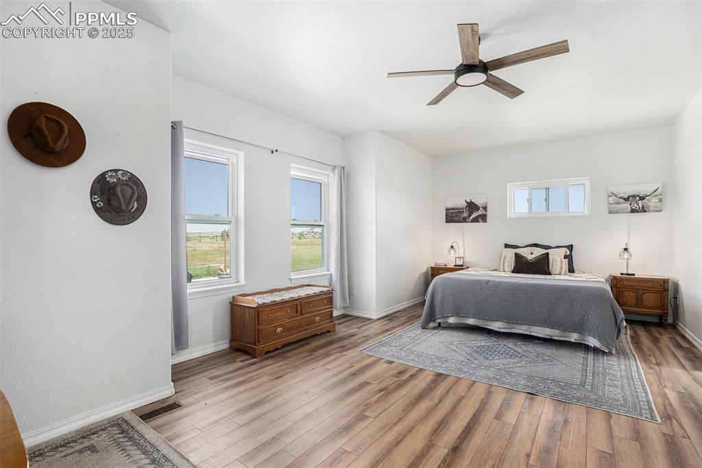 Image 10 of 24: Bedroom with multiple windows, a ceiling fan, and wood finished floors