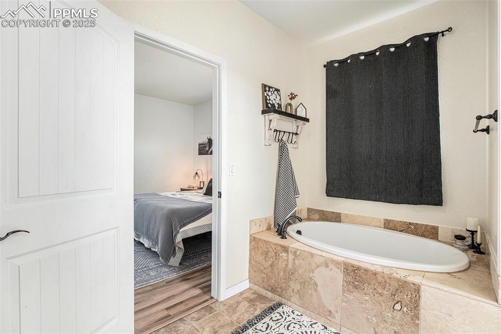 Image 12 of 24: Ensuite bathroom with a garden tub and baseboards