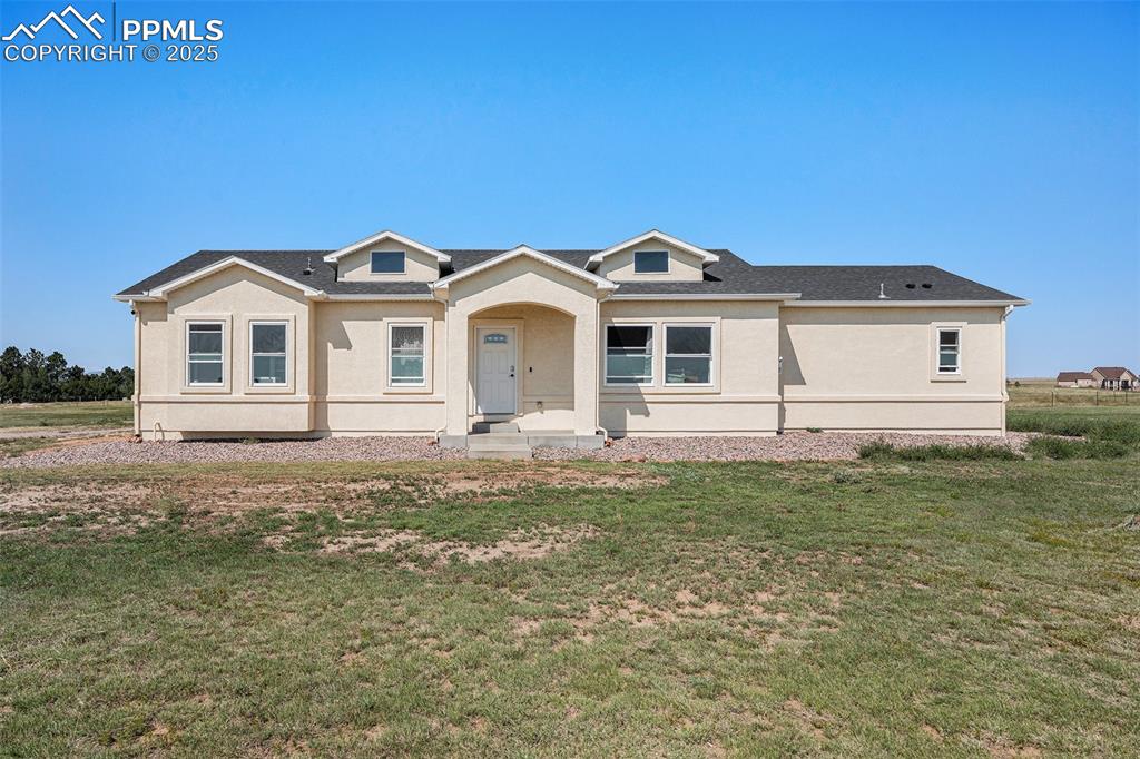 Image 24 of 24: View of front of house with a front lawn, roof with shingles, and stucco si