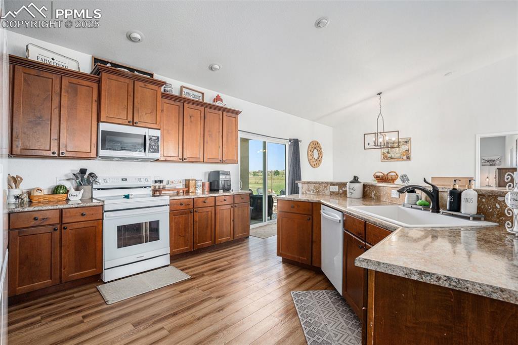Image 9 of 24: Kitchen featuring lofted ceiling, white appliances, light wood-style floori