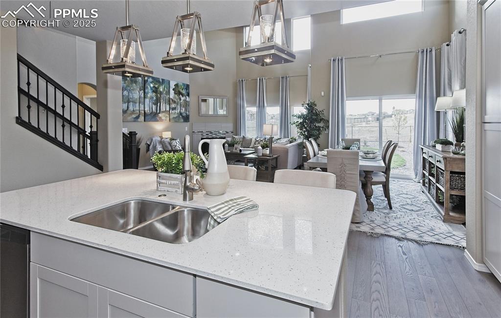 Image 10 of 30: Kitchen featuring a kitchen island with sink, light stone counters, light w