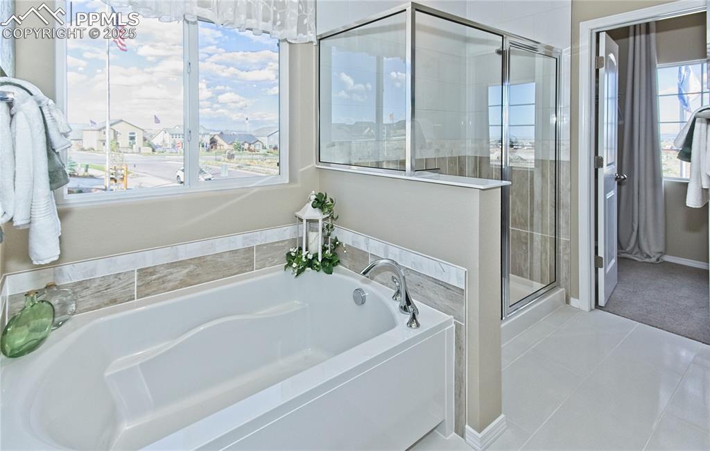 Image 25 of 30: Full bathroom with a shower stall, a garden tub, and light tile patterned f