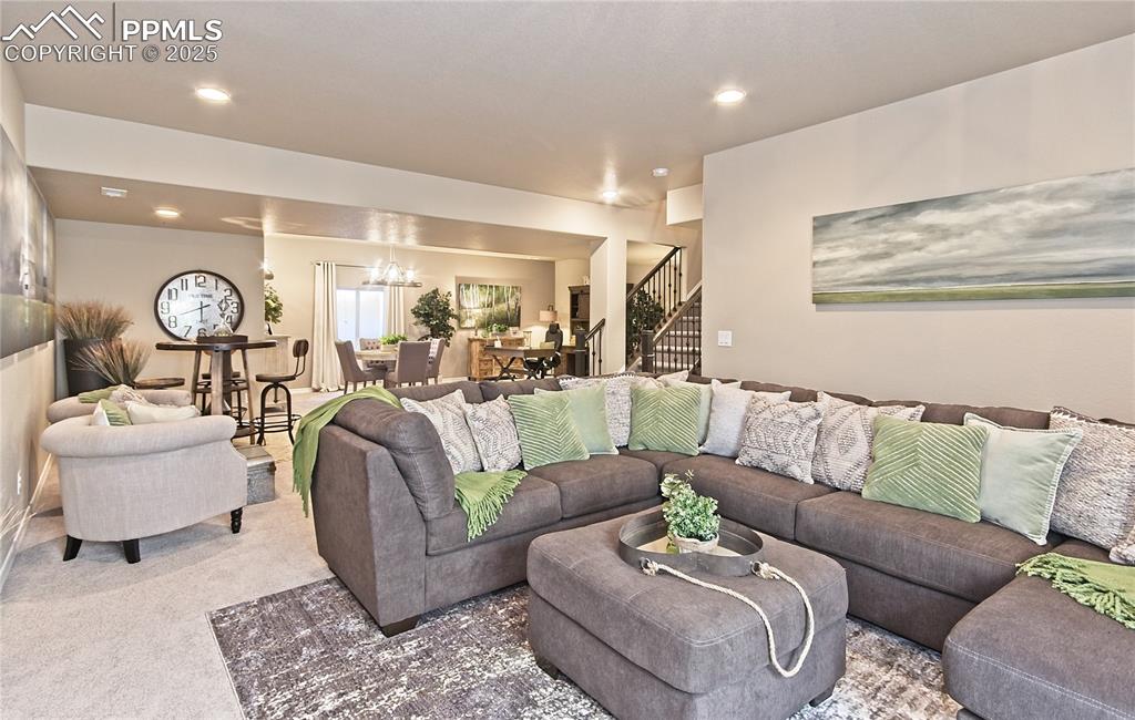 Image 28 of 30: Living area featuring stairway, carpet, a chandelier, and recessed lighting