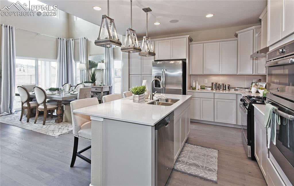 Image 9 of 30: Kitchen with decorative backsplash, a breakfast bar, appliances with stainl