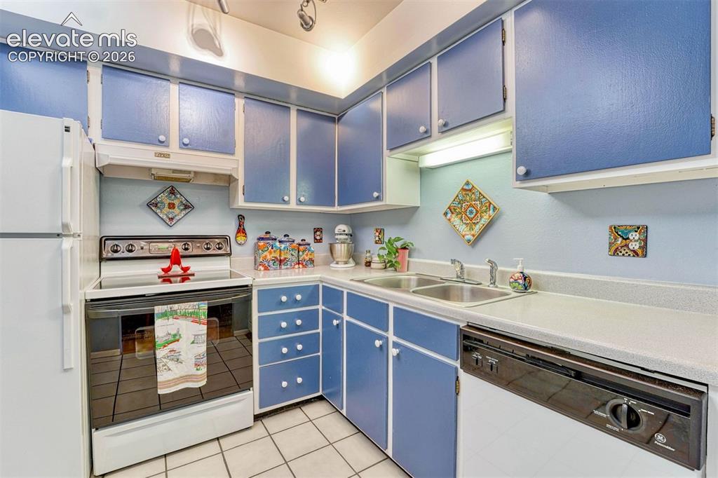 Image 11 of 35: Kitchen featuring blue cabinetry, white countertops, a double basin stainle