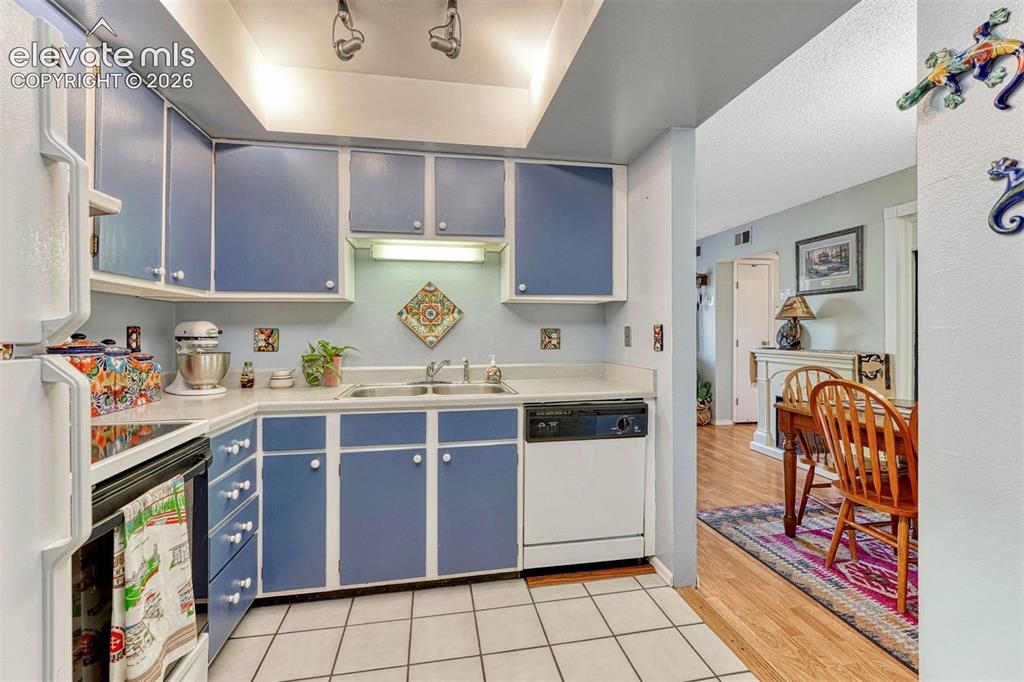 Image 13 of 35: Kitchen featuring blue cabinetry with white trim, white square tile floorin