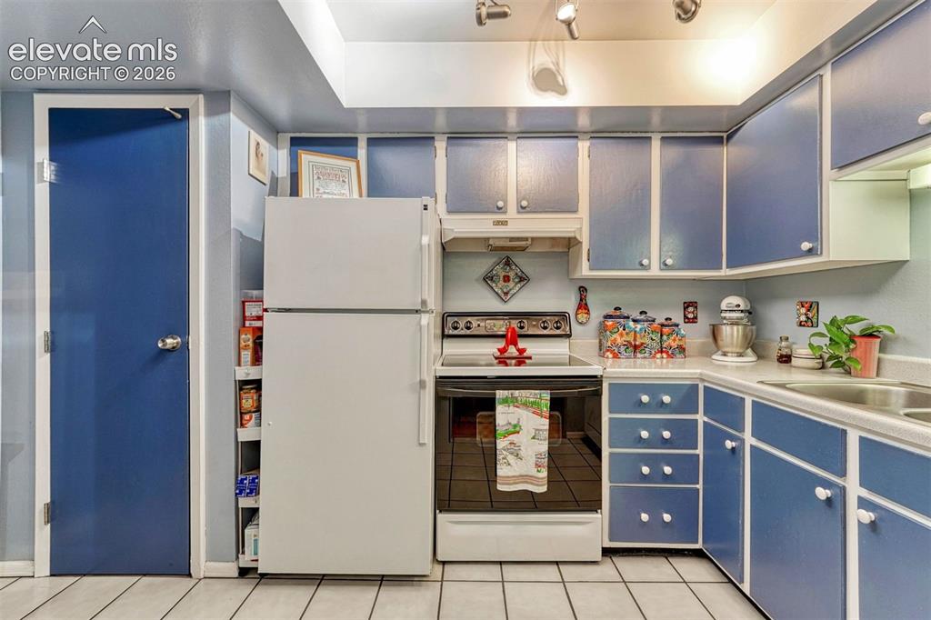 Image 14 of 35: Kitchen featuring blue cabinetry, white countertops, tile flooring, a built