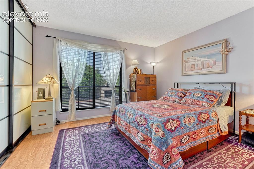 Image 16 of 35: Bedroom featuring wood-finish flooring, a large window with blinds and shee