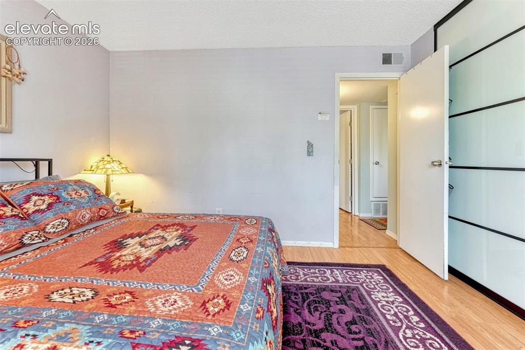 Image 18 of 35: Bedroom featuring light purple walls, wood-finish flooring, and a flat whit