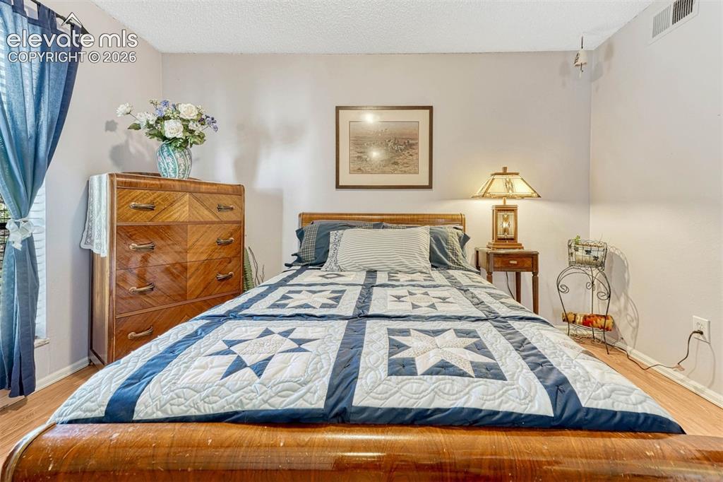 Image 20 of 35: Bedroom featuring wood-finish flooring, light-toned wall paint, and a textu