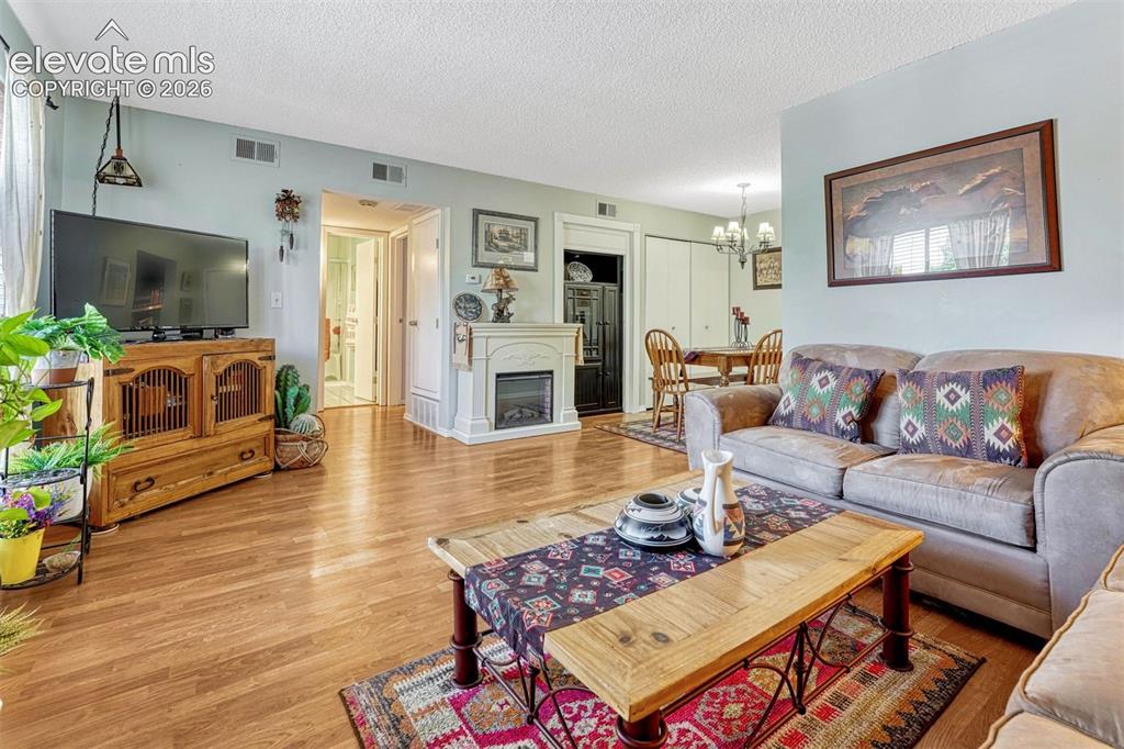 Image 7 of 35: Open-concept living space featuring wood-finish flooring, a white mantel wi