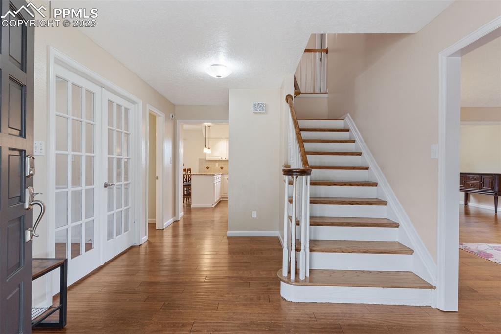 Image 4 of 45: Beautiful double-door entry with wood floors and light interior colors.