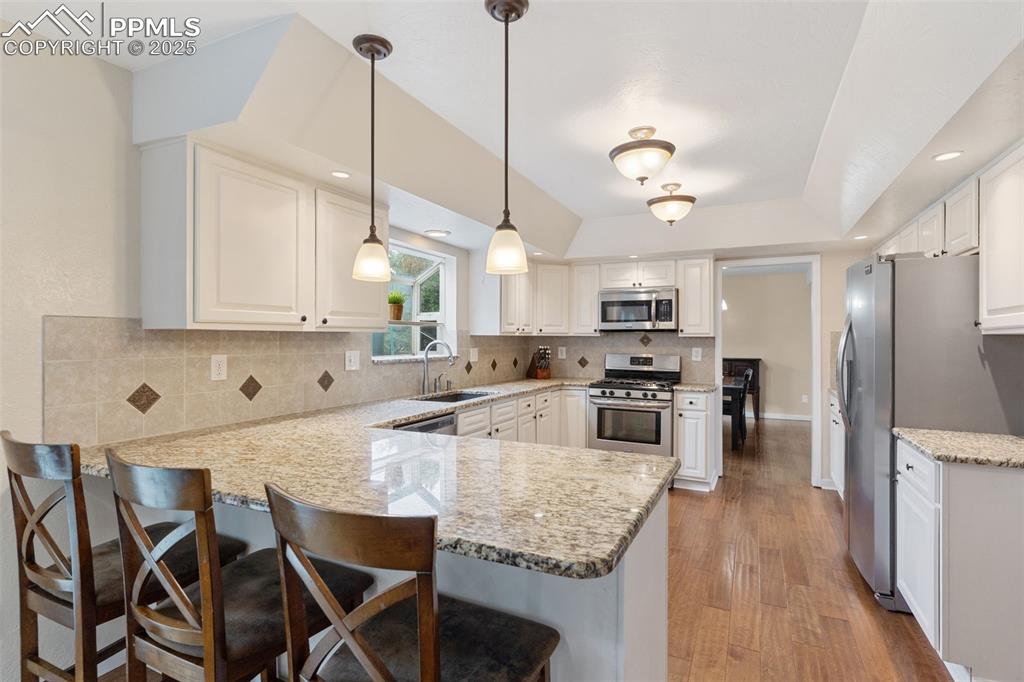 Image 6 of 45: Updated kitchen with granite counters, tile backsplash, new paint, wood flo