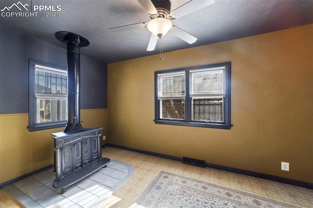 Image 11 of 41: FAmily room with a wood stove, a textured ceiling, light floors, and ceilin