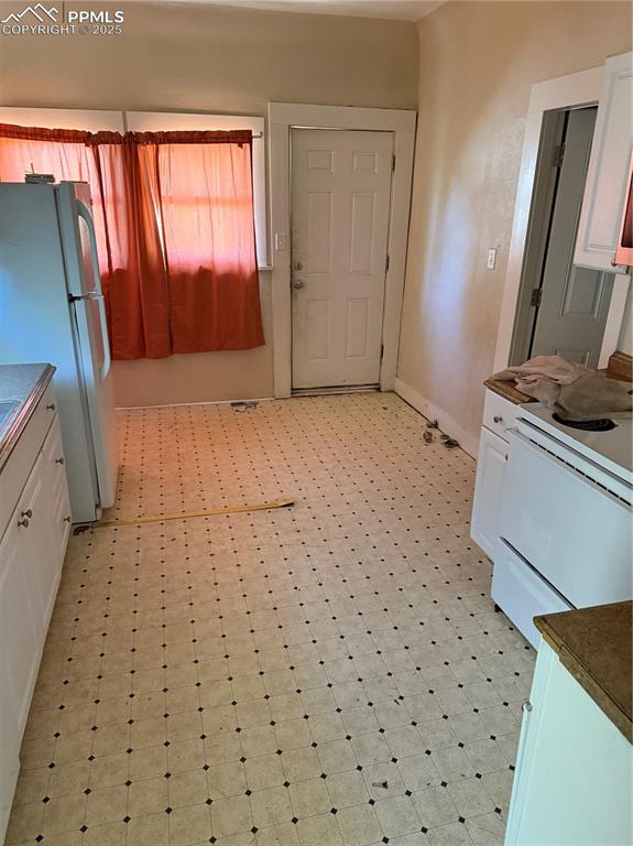 Image 2 of 11: Kitchen featuring fridge, range, white cabinetry, and light flooring