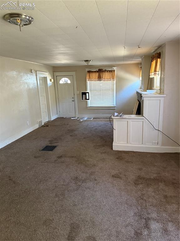 Image 4 of 11: Unfurnished living room with carpet and baseboards