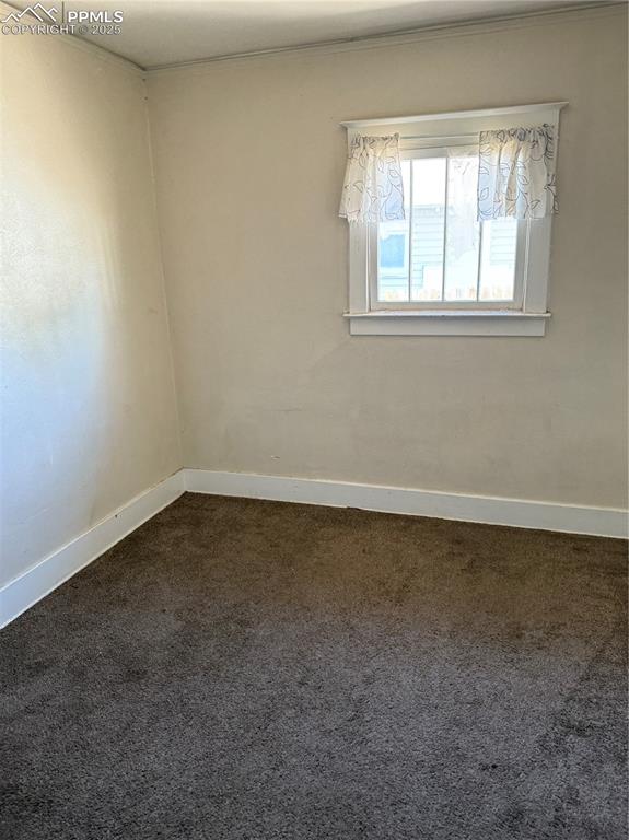 Image 7 of 11: Unfurnished room with dark colored carpet and crown molding