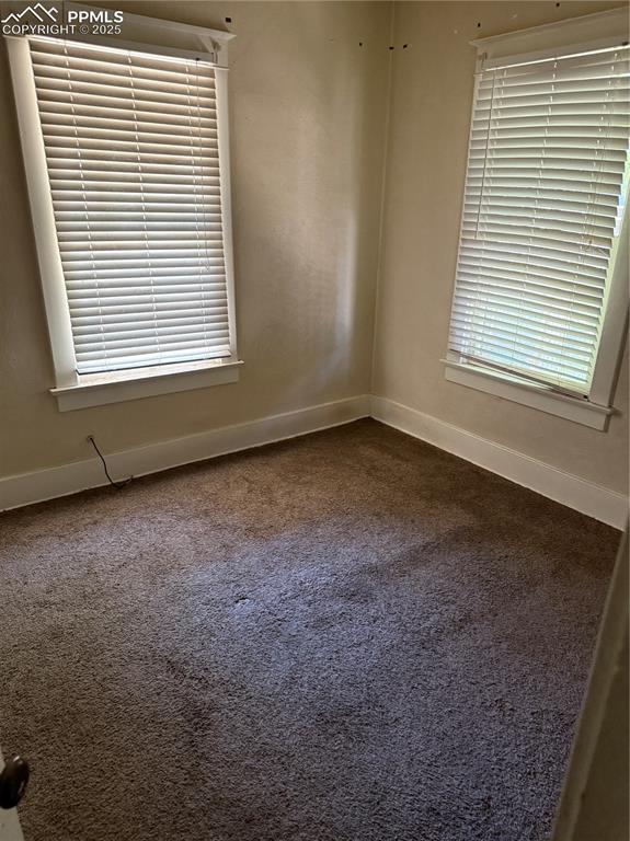 Image 8 of 11: Empty room with baseboards and dark carpet