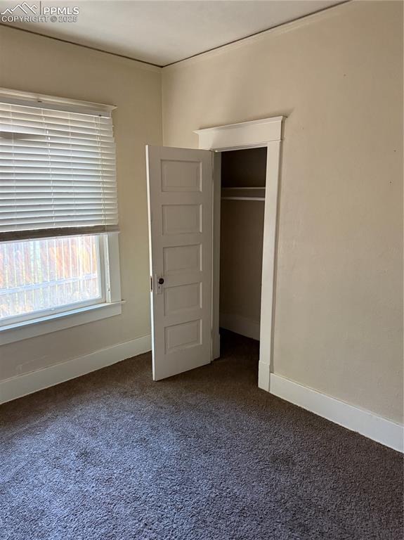 Image 9 of 11: Unfurnished bedroom featuring dark colored carpet and a closet