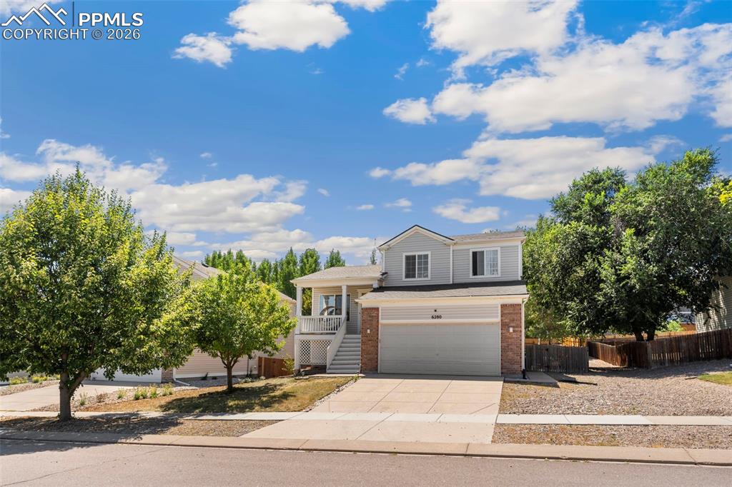 Image 2 of 25: View of front facade with brick siding, driveway, an attached garage, cover