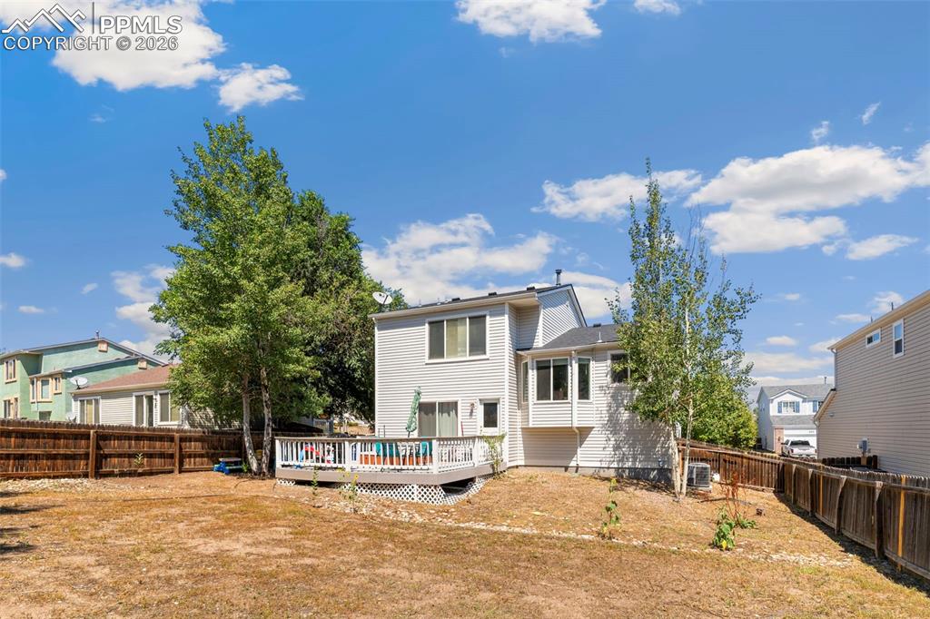 Image 25 of 25: Rear view of house with a wooden deck, a fenced backyard, and a residential